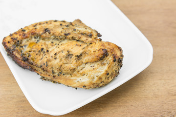 chicken breast with spicy ingredient grilled on a white plate, close up