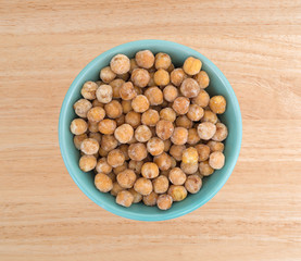 A serving of honey roasted chickpeas in a bowl atop a wood table.