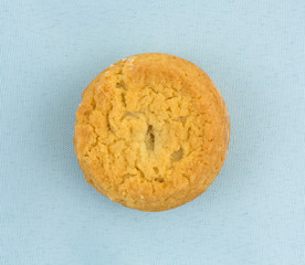 Top view of a single sugar cookie with hazelnut filling on a blue cloth napkin.