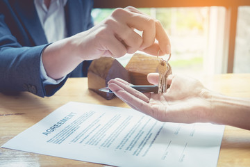 Agents are giving house keys of customer and holding dollar us bank at agency office. Agreement concept.