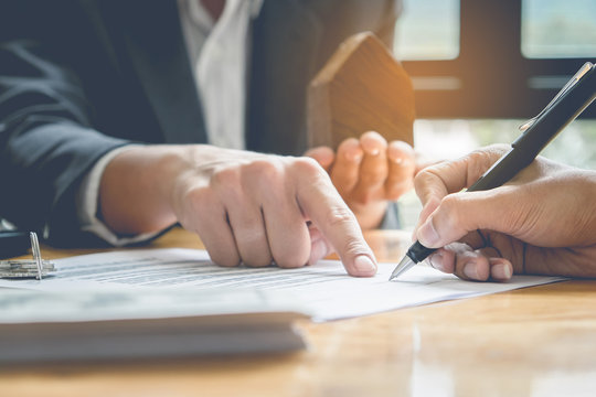 Close up of Business man pointing and signing agreement for buying house. Bank manager concept.