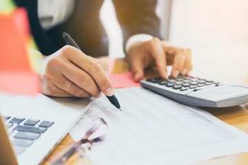 Fototapeta premium Close up Business man using calculator and laptop computer for calculating with finance paper, tax, accounting, Accountant concept.