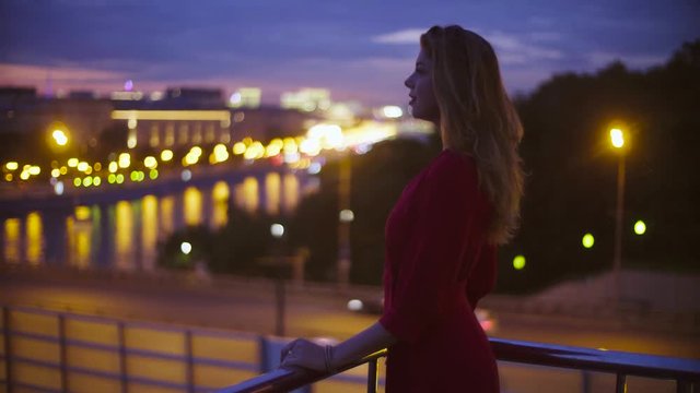 Young woman in red dress is standing near parapet