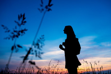 Girl enjoys the sunrise with a view of the beautiful sky. Portrait in profel. Traveler's style