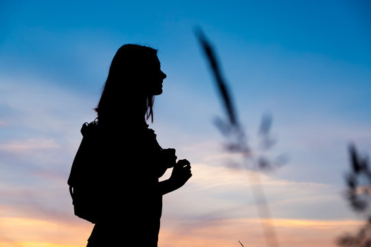 Girl enjoys the sunrise with a view of the beautiful sky. Portrait in profel. Traveler's style