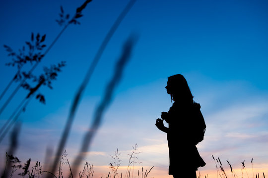 Girl enjoys the sunrise with a view of the beautiful sky. Portrait in profel. Traveler's style