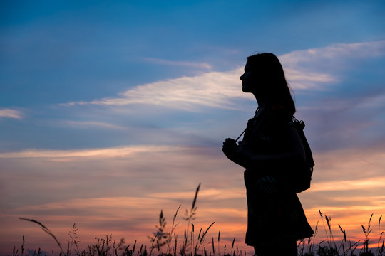 Girl enjoys the sunrise with a view of the beautiful sky. Portrait in profel.