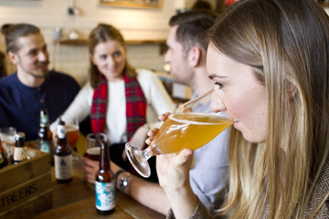 Young woman tasting beer in pub, Dorset, Bournemouth, England