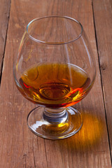 Cognac in a glass goblet on the old wooden table