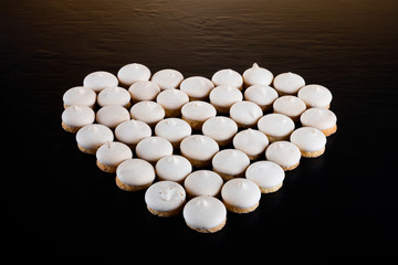 Small cookies laid in the shape of heart on black background. Selective focus. Shallow depth of field