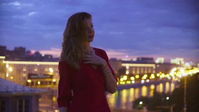 Young woman in red dress is standing near parapet