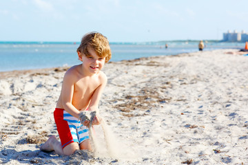 Little kid boy having fun on tropical beach