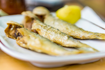 Close up of a dish with fresh fried horse mackerel. Light meals on hot summer days on the beach. Concept holiday summer lazy days. Shallow depth of focus.