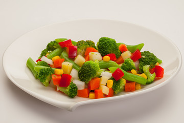 Vegetable mix with carrot, broccoli, paprika, green beans, corn and potato. On white plate