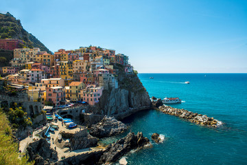 view of famous travel landmark destination Manarola, small mediterranean old sea town with harbour coast,Cinque terre National Park, Liguria, Italy. Summer sunny morning with tourists boat