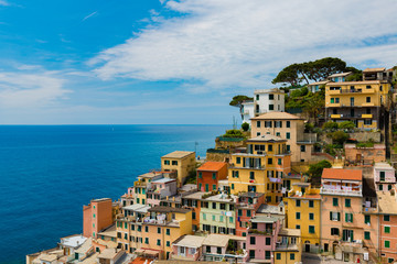 view of famous travel landmark destination Riomaggiore colorful houses, small mediterranean old sea town,Cinque terre National Park, Liguria, Italy. Summer sunny morning with clouds