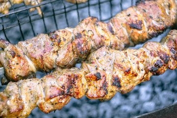 Marinated shashlik preparing on a barbecue grill over charcoal. Grilled kebab cooking on metal skewer. Roasted meat cooked at barbecue.