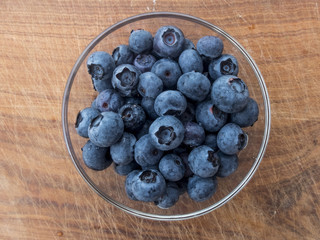 Blueberries in glass cup on wooden cutting board
