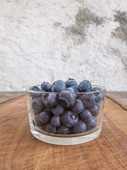 Blueberries in glass cup on wooden cutting board