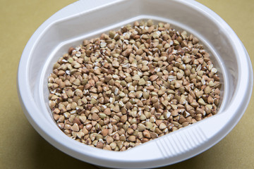 Piatto in plastica con del grano dentro su tavolo di colore chiaro omogeneo