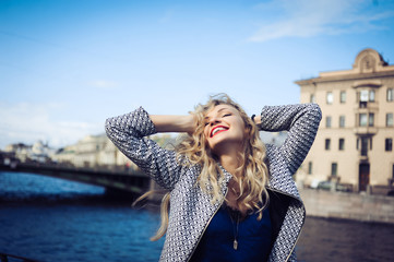 Fototapeta na wymiar close-up portrait of a young girl hipster beautiful blonde with red lips laughing and posing against the backdrop of the city