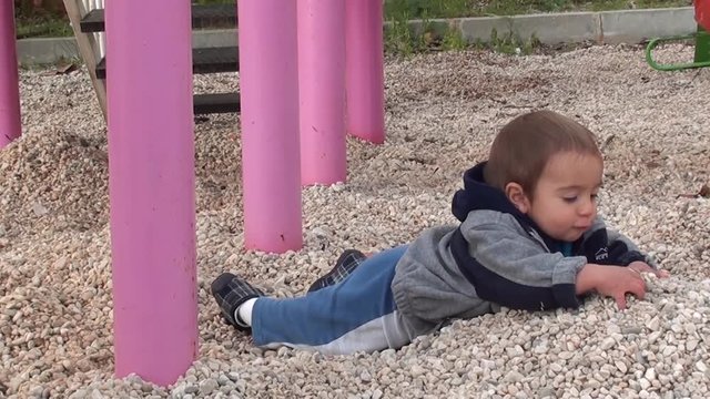 Charismatic toddler plays on gravels on children playground