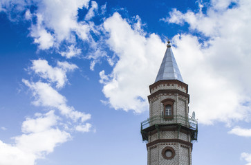 Fototapeta na wymiar Mosque of Sunni Muslims. Minaret against the blue sky with white clouds.