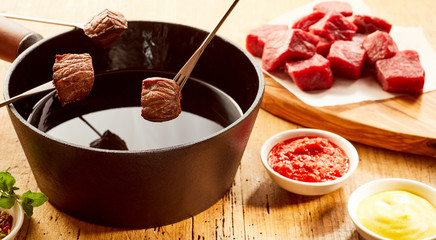 Fondue with meat bits over table with sauce