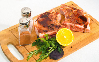 Two appetizing pieces, pork entrecote with sauce on a wooden cutting board with salt shaker and pepper and rosemary and lemon