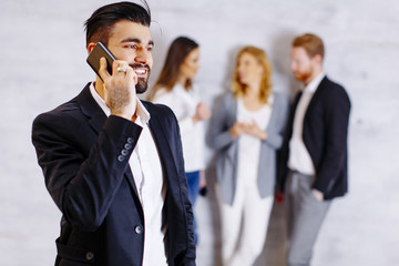 Businesspeople standing against the wall and using their mobile phones