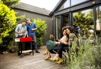 Friends grilling food and enjoying barbecue party outdoors