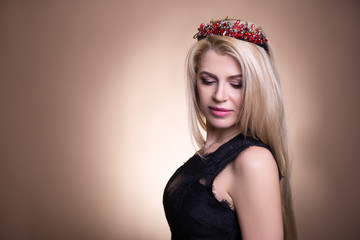 portrait of young beautiful blond woman in crown and space over beige