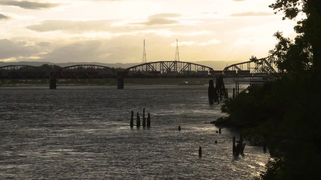A train going over the rail bridge between Portland, Oregon and Vancouver, Washington over the Columbia river near sunset. 