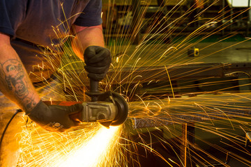 Worker using metal grinder, sparks 