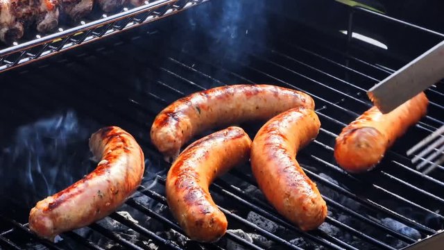 Sausages cooking on barbecue grill for summer outdoor party