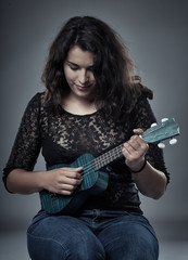 Fototapeta premium Young latino woman playing ukulele