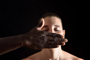 a hand covering  mouth of caucasian woman on black