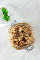 Eggplant caviar. Italian pesto of eggplant in a glass jar on a white marble table. Canning