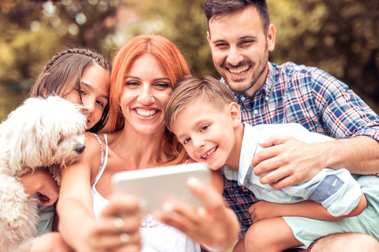 Portrait of happy family taking selfie outdoors