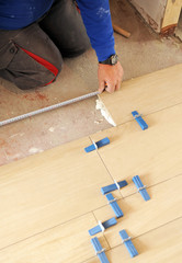 Bricklayer taking measurements with a meter during the placement of a new porcelain stoneware floor in the house
