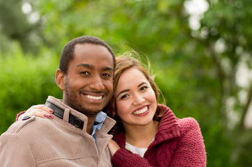 Beautiful and smiling happy interracial young couple in park in outdoors