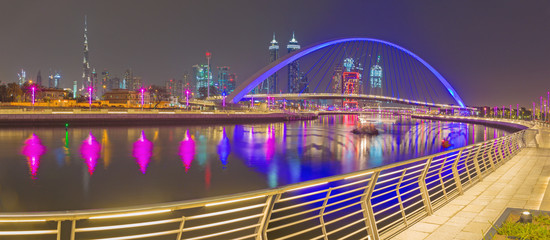 Fototapeta na wymiar Dubai - The evening skyline with the arched bridge over the new Canal and Downtown.
