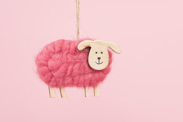 wooden and woolen decoration sheep on a pink background