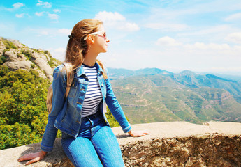 Naklejka premium Travel young woman sitting on the rocks, mountains Spain background and blue sky