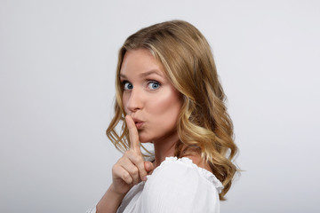 Blonde Frau mit Finger auf den Lippen