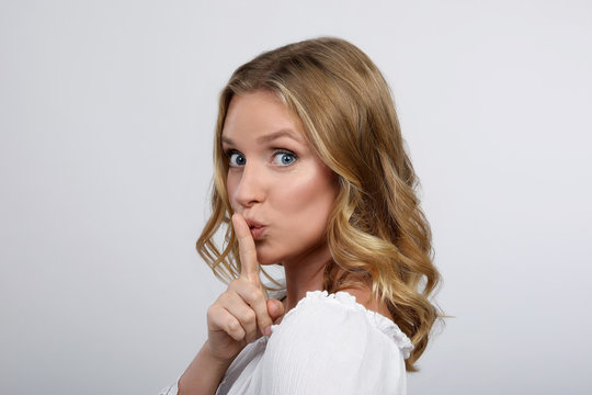 Blonde Frau mit Finger auf den Lippen