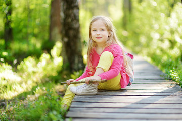 Naklejka na ściany i meble Cute little girl having fun during forest hike on beautiful summer day