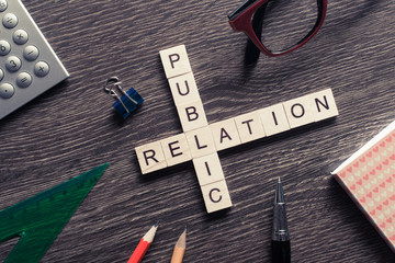 Public Relation crossword on office table collected of wooden cu