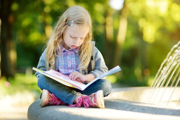 Adorable little schoolgirl studying outdoors on bright autumn day. Young student doing her homework. Education for small kids.