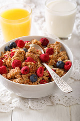 Baked granola with dried raspberries and blueberries, milk and juice close-up. vertical